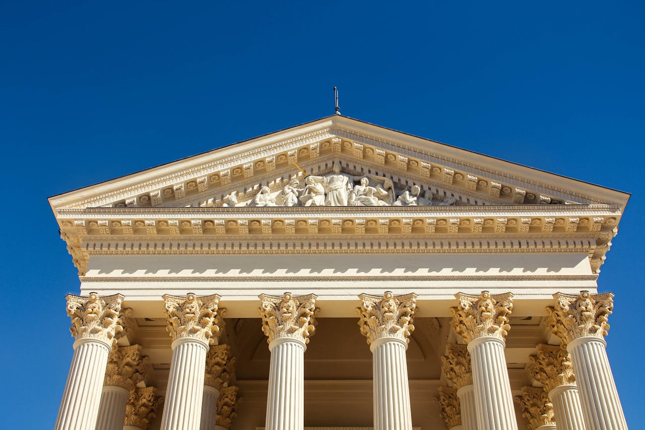 Close-up of a classical building with ornate columns and pediment under clear blue sky.