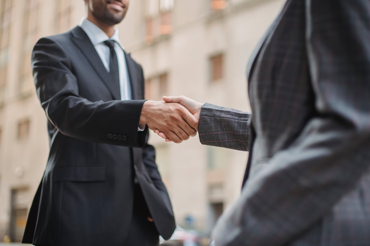 who-we-are Business professionals greeting each other with a handshake outdoors, symbolizing partnership.