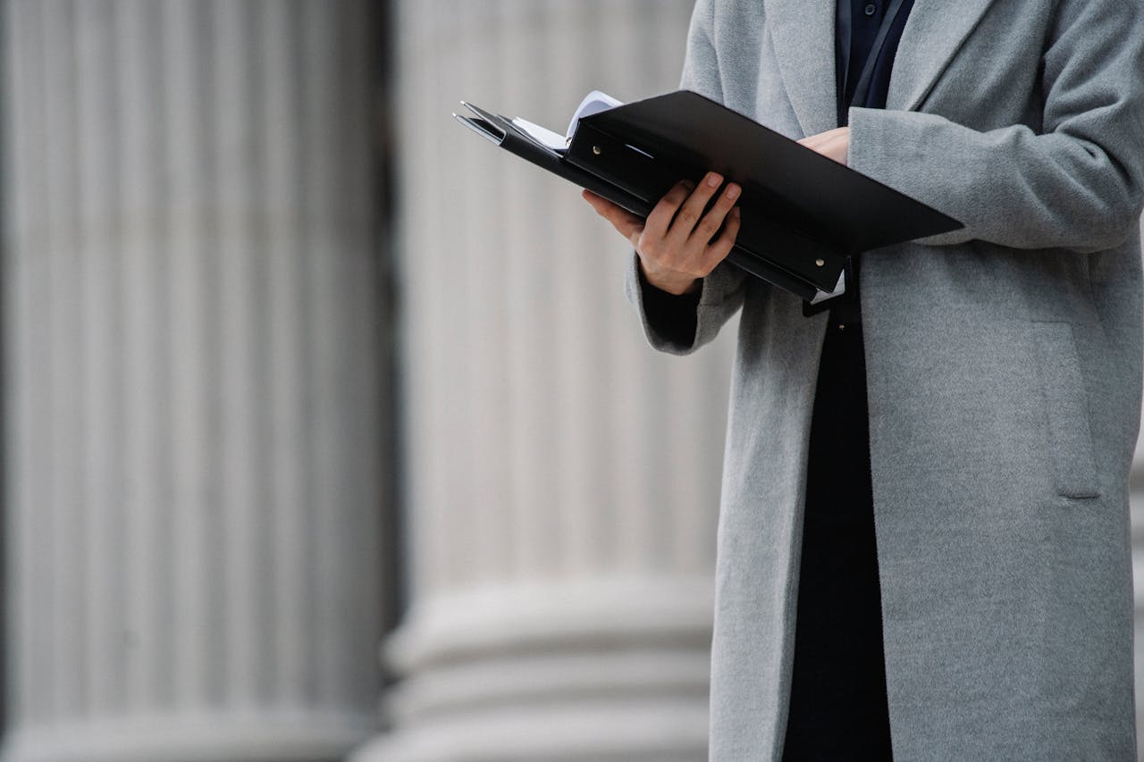 services-04 Crop unrecognizable businesswoman in gray coat standing on street with opened document folder and reading contract on autumn day