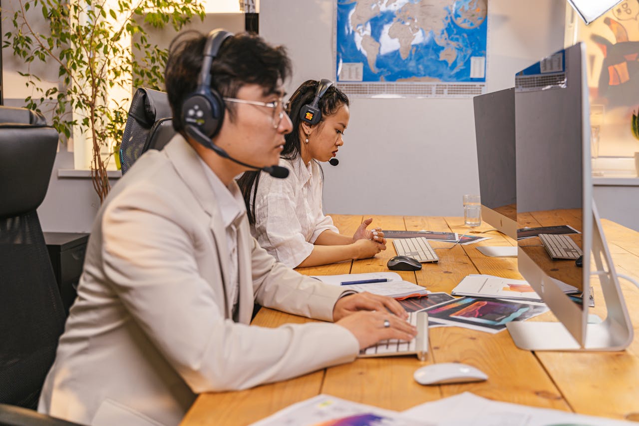 services-02 Call center agents working at computers with headsets in a modern office setting.