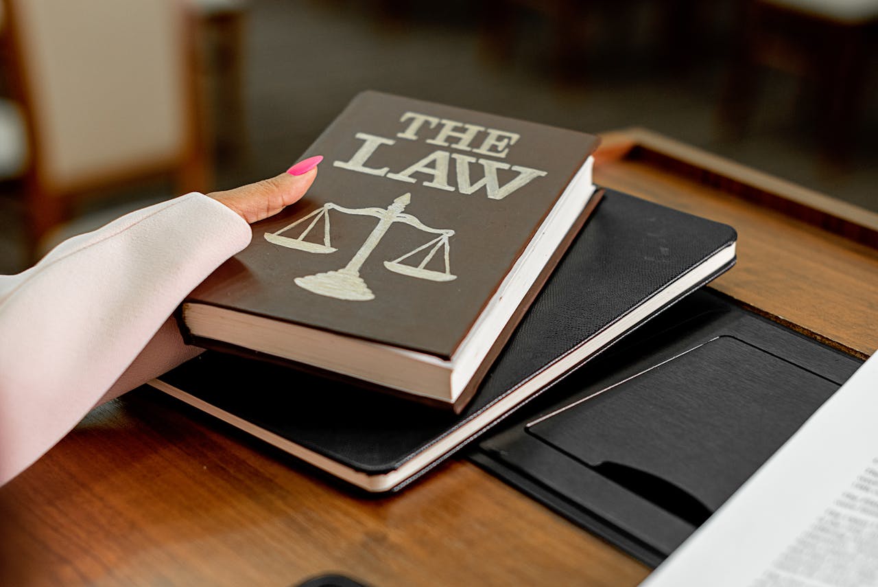 services-04 Closeup image of a law book titled 'The Law' on a wooden desk with scales of justice.